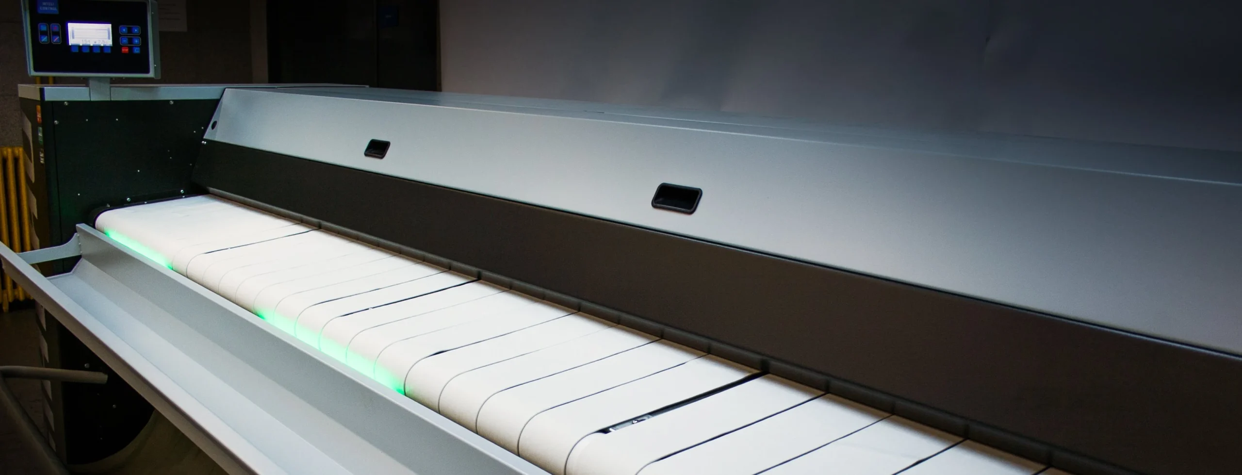 Commercial wall ironer with heated rollers and feeding conveyor, designed for high-quality flatwork finishing in professional laundry environments.