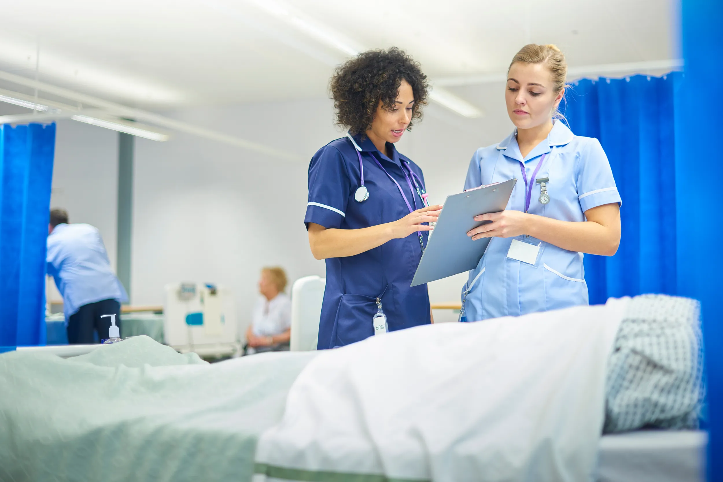 Healthcare Nurses with freshly laundered uniform standing by clean hospital bed