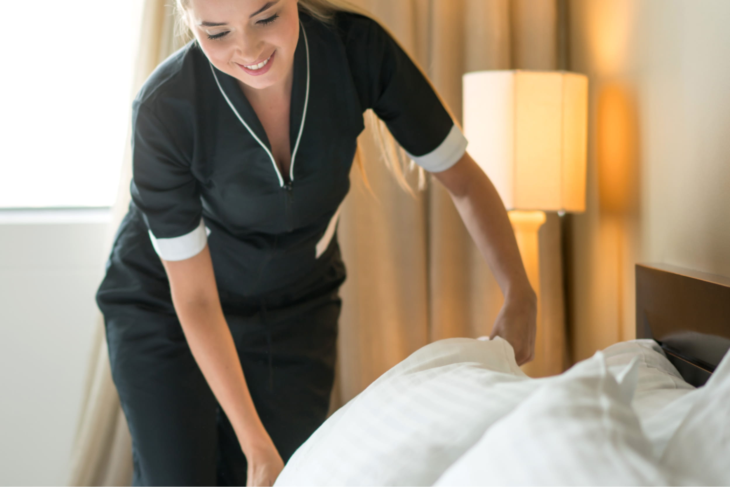 Hotel-staff-making-beds-in-hotel-room-with-clean-laundered-sheets