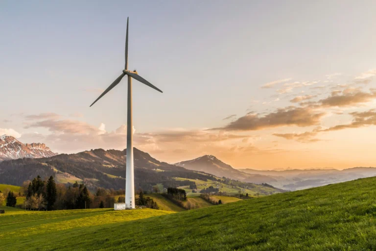 Wind turbine in a green landscape at sunset symbolizing Girbau’s Zero Energy approach with up to 35% energy recovery through residual heat reuse.