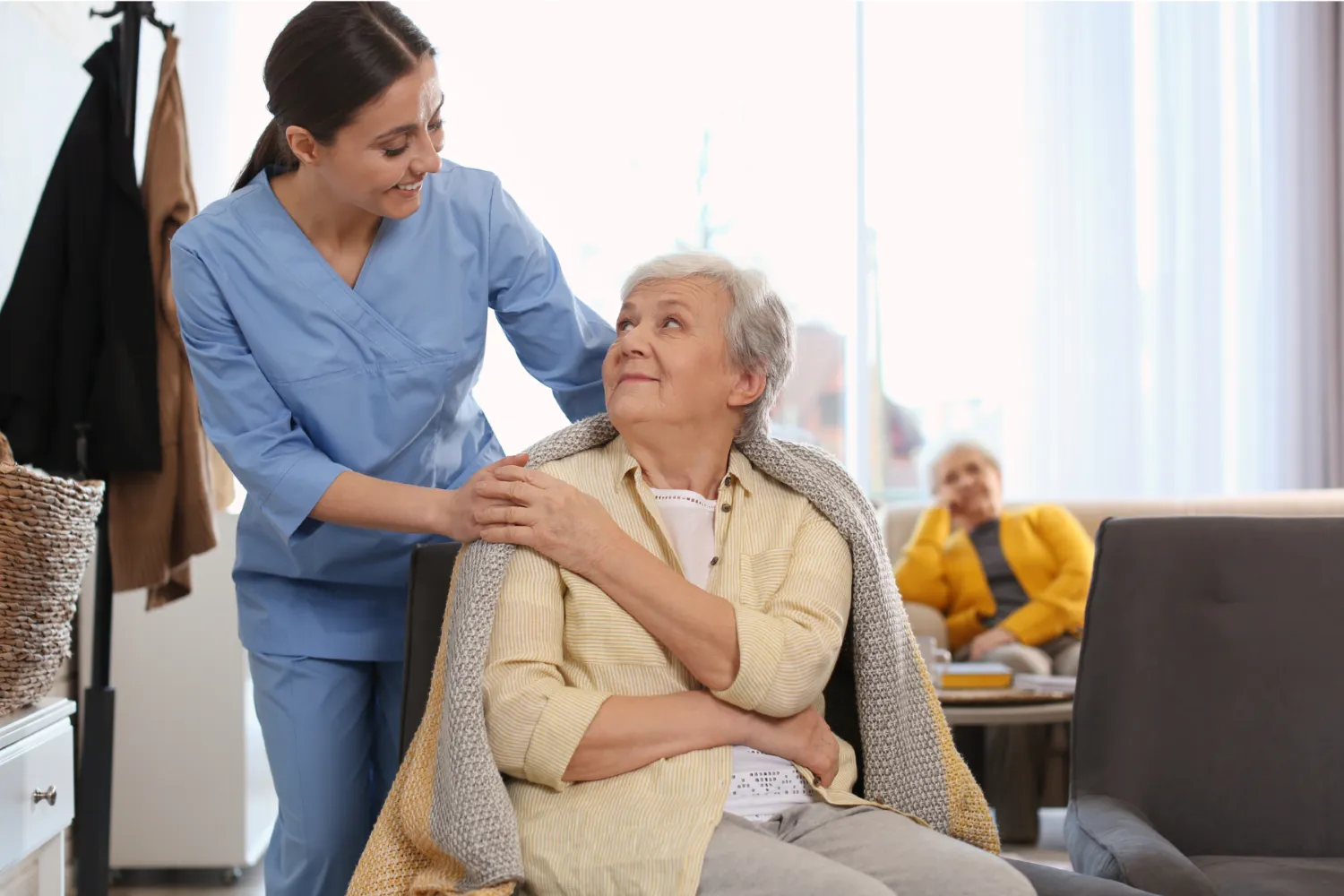 Care home nurse assisting patient with blanket