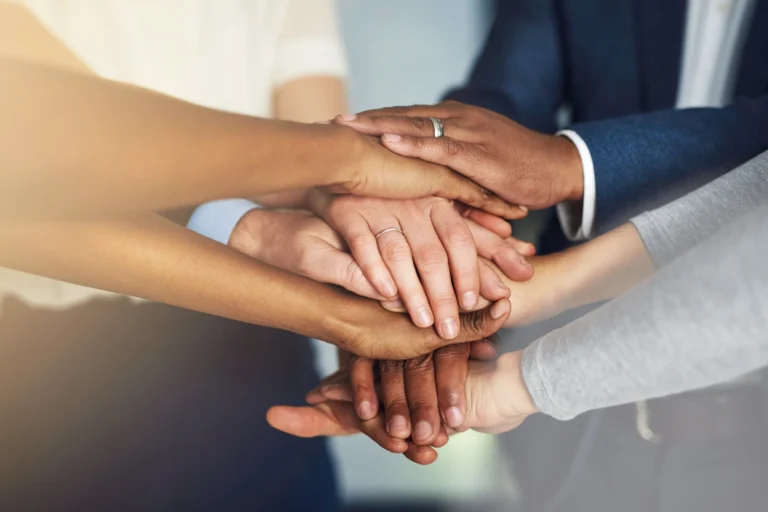 A diverse group of colleagues stacking their hands together in a show of teamwork and unity.