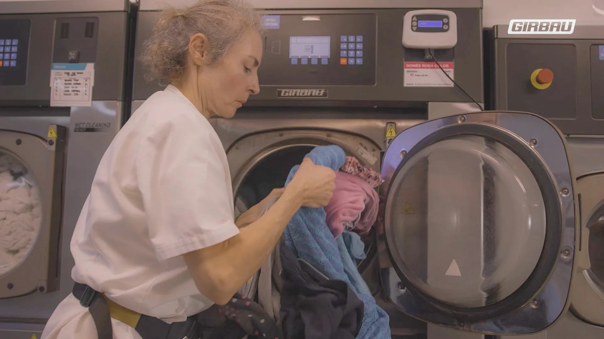 Operaria cargando textiles sanitarios en una lavadora Girbau, garantizando higiene y correcta desinfección en lavandería hospitalaria.