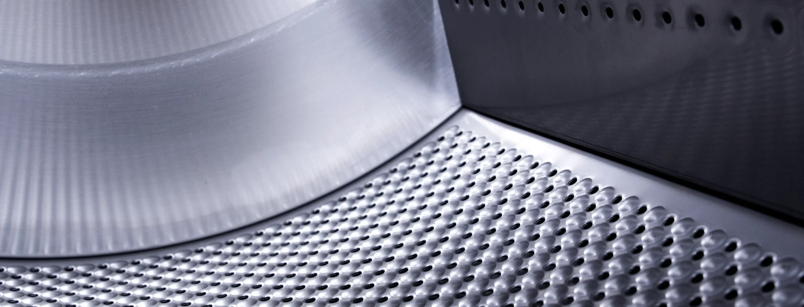 Gros plan sur le tambour en acier inoxydable d’une laveuse commerciale, représentant les machines de blanchisserie professionnelle à haute performance.