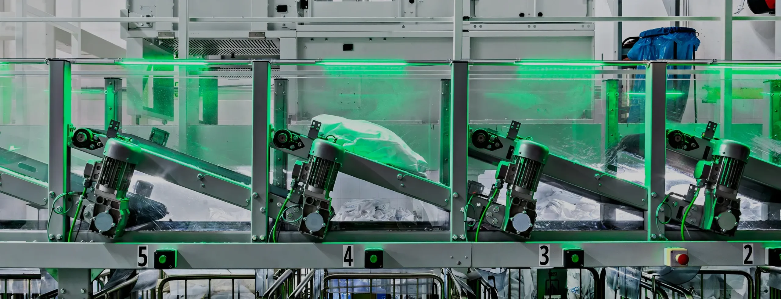 Ligne de tri de linge automatisée avec convoyeurs motorisés, représentant les systèmes de lavage performants et le tri RFID pour laveuses industrielles.