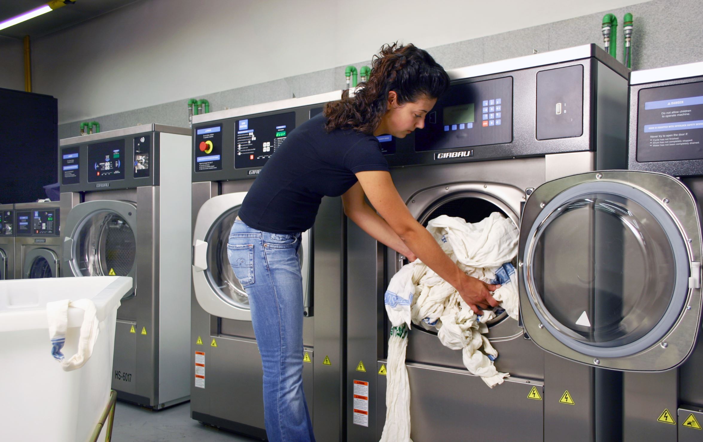 Girl loading a Girbau's commercial washer at a laundromat