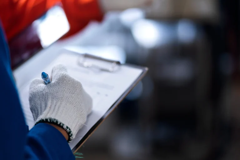 Operatore che scrive su un clipboard durante un controllo qualità, illustrando l’impegno di azienda Girbau e le attrezzature per lavanderia.