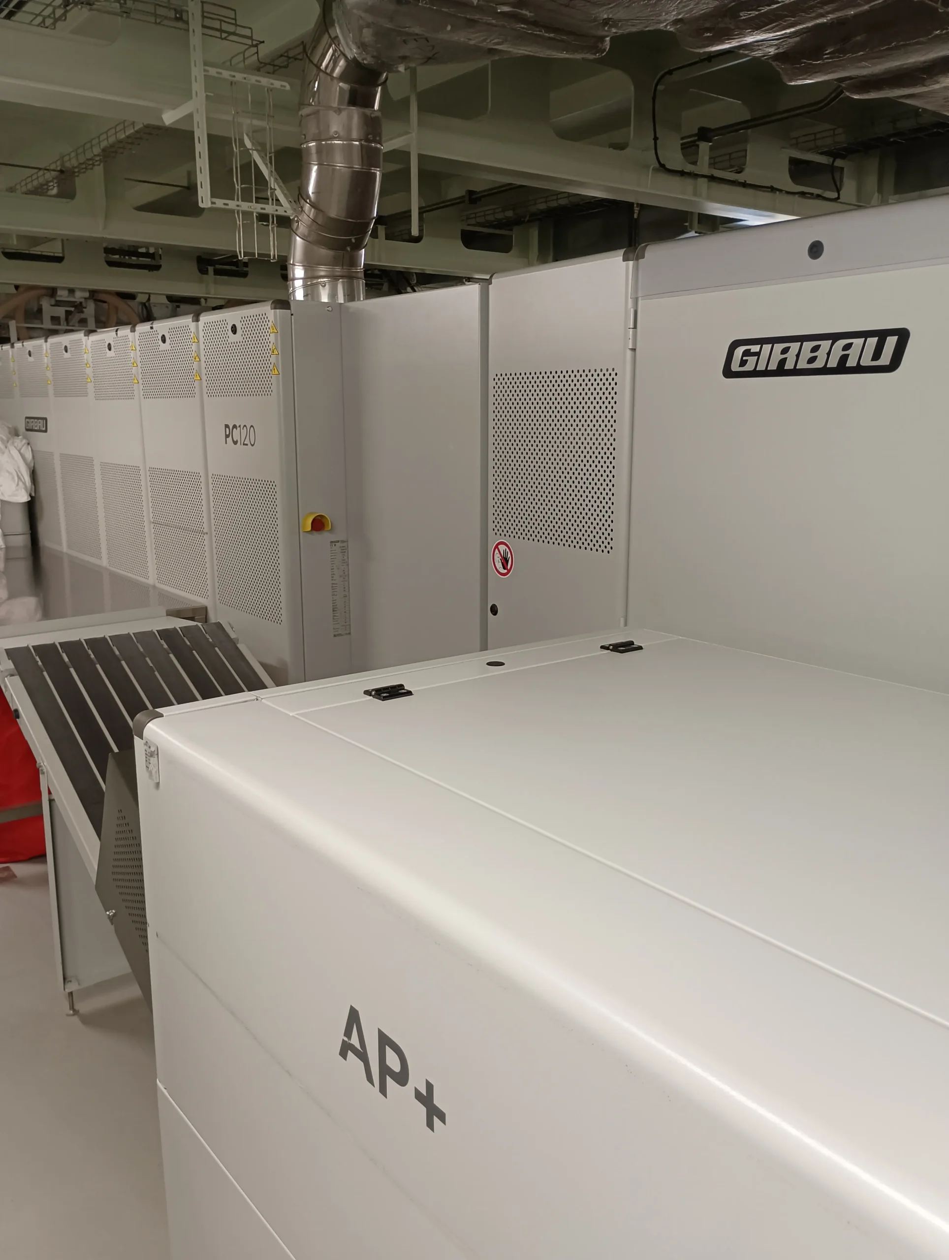 Girbau auxiliary equipment integrated with an industrial ironer at the MSC World Europa laundry facility.