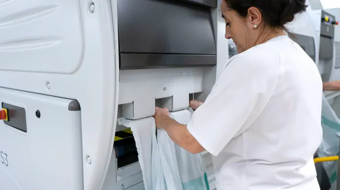 Person loading a garment into an industrial laundry machine.