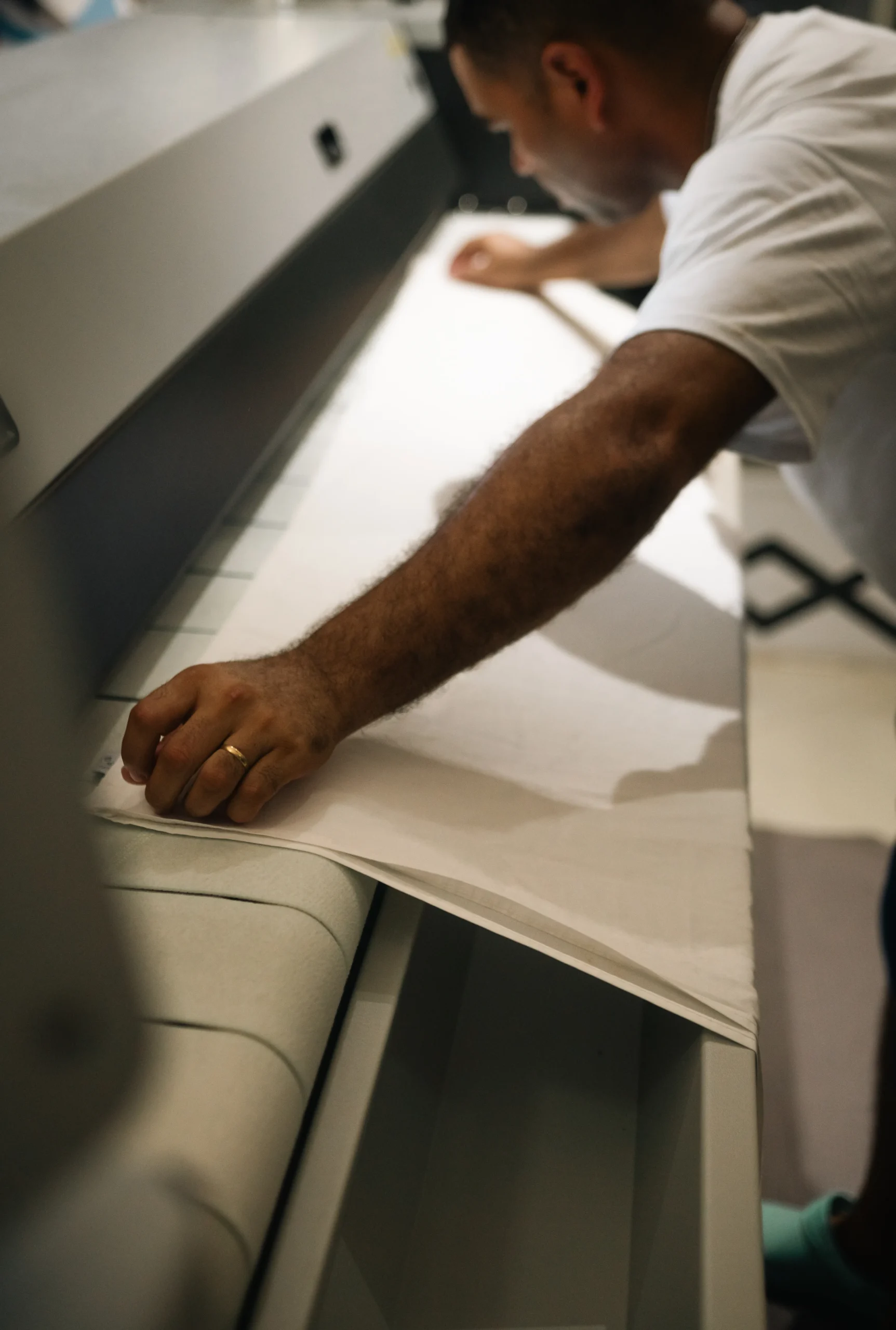 Laundry worker feeding bed linen into a flatwork ironer for efficient textile finishing.
