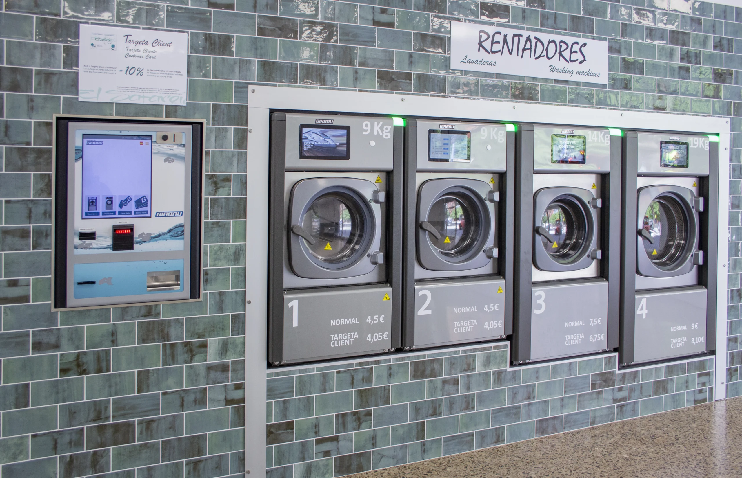 Industrial washing machines with touchscreen payment system at El Safareig self-service laundry.